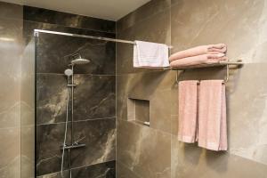 ein Badezimmer mit einer Dusche und Handtüchern auf einem Kleiderständer in der Unterkunft Nest Apartments in Gjakove