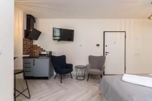 een slaapkamer met een bed en 2 stoelen en een tafel bij Doki Studio Stocznia by Grand Apartments in Gdańsk