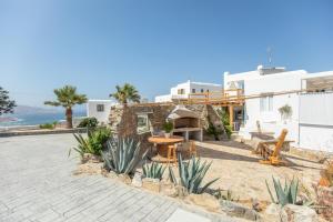 a patio with a table and benches in front of a building at Levantes House Mykonos in Ano Mera