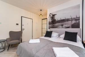 een slaapkamer met 2 bedden en een stoel bij Doki Studio Stocznia by Grand Apartments in Gdańsk