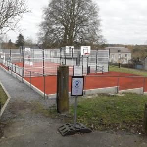 una pista de tenis con un cartel delante en Gîte Les Cent Fontaines, en Modave