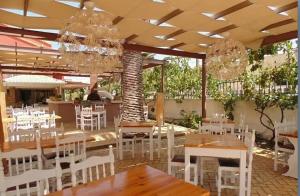 a restaurant with white chairs and tables and a chandelier at The Blue Sea Hotel in Agios Georgios