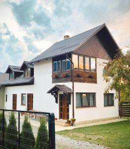 uma casa branca com um telhado preto em Casuta Fulgu - sa te simti ca acasa! em Borşa