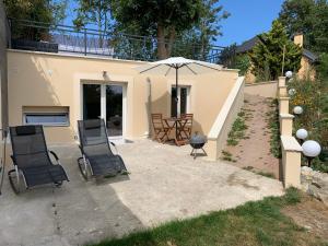 - une terrasse avec 2 chaises et un parasol dans l'établissement Maisonnette cosy bord de Seine 30min paris, à Carrières-sous-Poissy