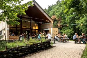 Eine Gruppe von Menschen sitzt an Tischen vor einem Restaurant in der Unterkunft Starling in Oud-Turnhout