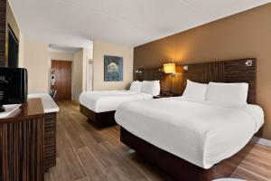 a hotel room with two beds and a flat screen tv at Ramada by Wyndham Harrisburg/Hershey Area in Harrisburg