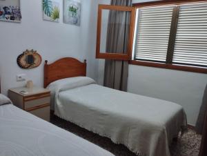 a hotel room with two beds and a window at Casa los Cactus in Playa Migjorn