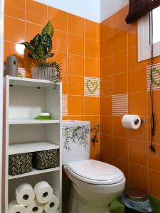 baño de azulejos de color naranja con aseo y rollos de papel higiénico en Céntrico Rota Beach. en Rota