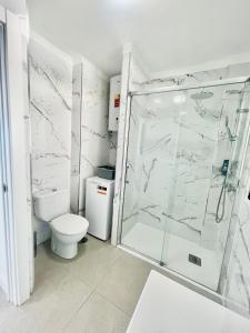 a white bathroom with a shower and a toilet at Royal View Apartment - Playa de Las Americas in Playa de las Americas