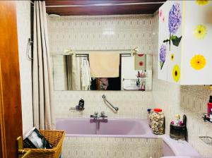 uma casa de banho com uma banheira rosa e um espelho. em À casetta em Albertacce