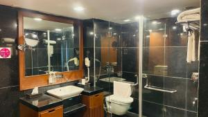a bathroom with a toilet and a shower and a sink at Royal Orchid Central Kireeti Hampi in Hampi +38 photos