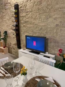 einen Fernseher auf einem weißen Tisch mit Weingläsern in der Unterkunft I Fiori di Colle, l’anima Toscana “Loft” in Colle di Val d’Elsa