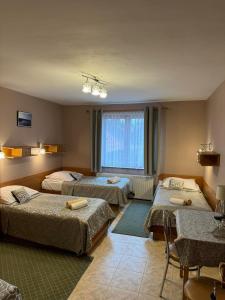 ein Zimmer mit drei Betten und einem Fenster in der Unterkunft Galant Hotel in Wieliczka
