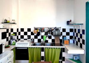 uma cozinha com um lavatório e uma parede xadrez em preto e branco em The Green House on the sea em Pozzallo