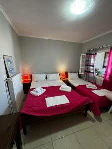 a bedroom with two beds with red sheets at xara house in (( Filaréton ))