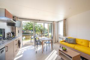 a kitchen and living room with a yellow couch and a table at Vakantiepark Vlinderloo in Enschede