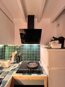 a kitchen with a stove top oven with green tiles at "Lou Pataquet" in Marseille