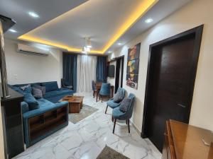 ein Wohnzimmer mit einem blauen Sofa und Stühlen in der Unterkunft Porto said بورتوسعيد غرفتين وصاله in Port Said