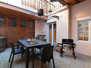 eine Terrasse mit einem Tisch, Stühlen und einem Grill in der Unterkunft GÎTE **** L'ATELIER DU TONNELIER in Ribeauvillé