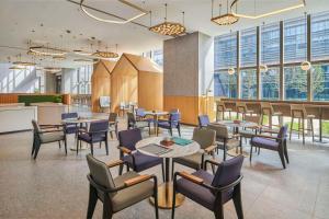 un restaurant avec des tables, des chaises et des fenêtres dans l'établissement Hilton Garden Inn Suzhou Wuzhong, à Suzhou