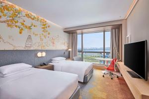 a hotel room with two beds and a flat screen tv at Hilton Garden Inn Suzhou Wuzhong in Suzhou