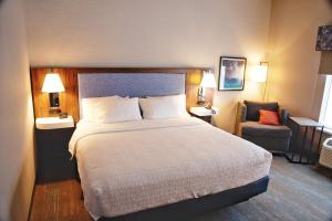 Hampton Inn West Wichita Goddard في Goddard: غرفة فندقية بسرير كبير وكرسي