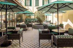 un restaurante con mesas, sillas y sombrillas en Anglo American Hotel Florence, Curio Collection By Hilton en Florence