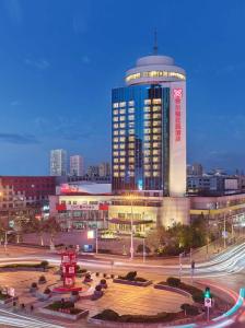 ein großes Gebäude mit einem Uhrturm in einer Stadt in der Unterkunft Hilton Garden Inn Anshan Haicheng in Anshan