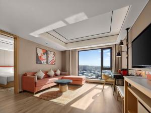 a living room with a couch and a tv at Hilton Garden Inn Anshan Haicheng in Anshan