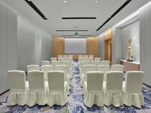 einen Konferenzraum mit weißen Stühlen und einem Bildschirm in der Unterkunft Hilton Garden Inn Anshan Haicheng in Anshan