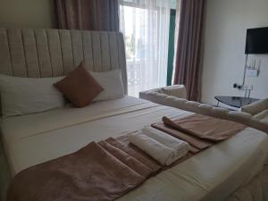 a bedroom with a large bed with towels on it at Tamara Studio Apartment in Shanzu in Mtwapa