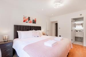 a white bedroom with a large bed with white sheets at Luxury Three Bedrooms Flat, Coulsdon CR5 in Coulsdon