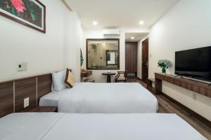 a hotel room with two beds and a flat screen tv at Hoang Linh Riverside Hotel Danang in Da Nang