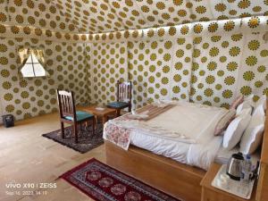 a bedroom with a bed and a table and a chair at Sam Safari Resort Jaisalmer in Jaisalmer