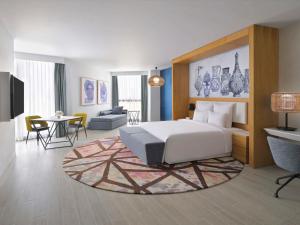 um quarto com uma cama e uma sala de estar em Mövenpick Hotel & Apartments Ghala Muscat em Mascate
