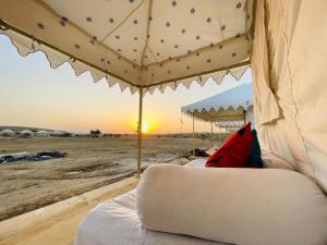 łóżko w namiocie z zachodem słońca w tle w obiekcie Sam Safari Resort Jaisalmer w mieście Jaisalmer