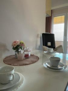 einen Tisch mit zwei Tassen und eine Vase mit Blumen darauf in der Unterkunft Apartmani "MARIJA" Golubac in Golubac
