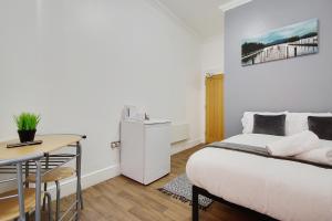 1 dormitorio con cama, mesa y escritorio en Azure Beach Hotel, en Bournemouth