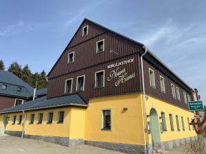 a brown and yellow building with a sign on it at Neues Haus - Berggasthof und Hotel in Kurort Oberwiesenthal