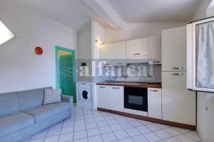 een woonkamer met een bank en een keuken bij Mare Bilo in Castiglione della Pescaia