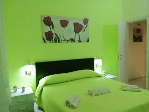 a green bedroom with a green bed with two towels at Casa vacanze valentino in Avola