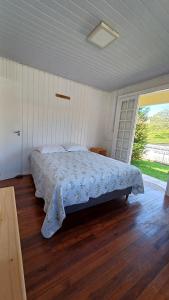 um quarto com uma cama e uma grande janela em Casa das Plantas em Gravatal