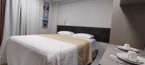 een slaapkamer met een bed en een tafel met borden bij Flat 109 Paradise Beach in João Pessoa