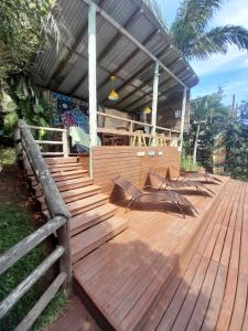 a wooden deck with wooden stairs and a building at Pousada Baia Rosa in Praia do Rosa