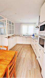 アギラスにあるFrente al marの白いキャビネットと木製のテーブルのあるキッチン