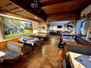 ein Restaurant mit Tischen und Stühlen und ein großes Gemälde an der Wand in der Unterkunft Pension Loiplstüberl in Bischofswiesen