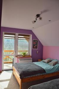1 dormitorio con paredes moradas, 1 cama y ventana en Agroturystyka w Świcie en Tuchola