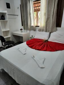 Un dormitorio con una cama blanca con una falda roja. en Pousada Flor Dália, en Natal