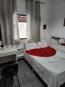 a bedroom with a bed and a desk and a chair at Pousada Flor Dália in Natal