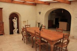 a wooden table and chairs in a room with a statue at Maison de charme en pierre in Morville